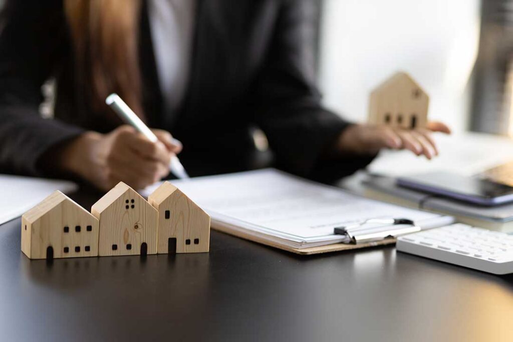 A couple and their real estate advisor reviewing home purchase documents at a kitchen table.