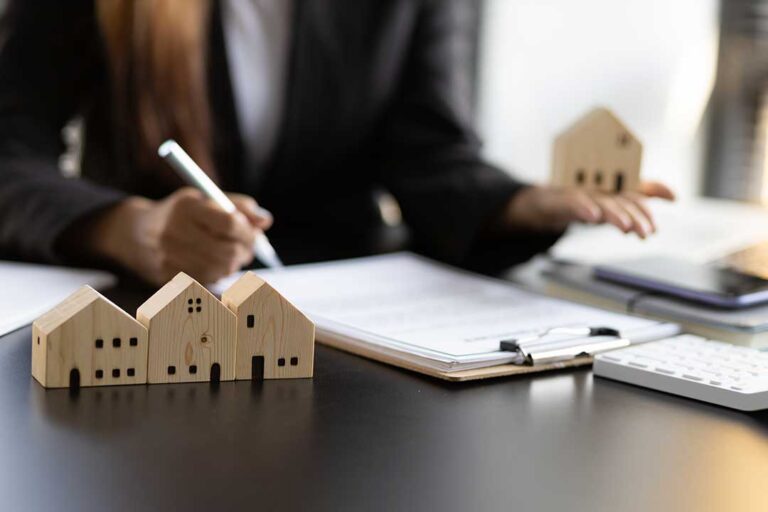 A couple and their real estate advisor reviewing home purchase documents at a kitchen table.
