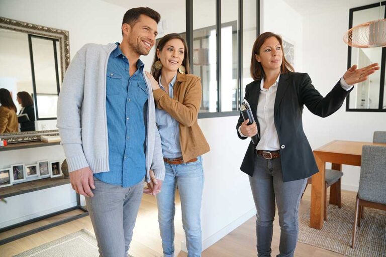 A family packing household items into cardboard boxes in a sunny, well-lit living room.